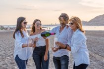 Pais maduros alegres e filhas jovens batendo copos de vinho e rindo enquanto comemoram o reencontro familiar à noite no resort — Fotografia de Stock