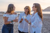 Mutter und kleine Töchter klimpern mit Weingläsern und lachen, während sie abends im Resort ein Familientreffen feiern — Stockfoto