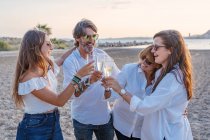 Fröhlich erwachsene Eltern und kleine Töchter klimpern mit Weingläsern und lachen, während sie abends im Resort ein Familientreffen feiern — Stockfoto