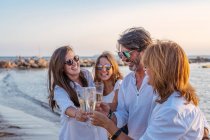 Fröhlich erwachsene Eltern und kleine Töchter klimpern mit Weingläsern und lachen, während sie abends im Resort ein Familientreffen feiern — Stockfoto