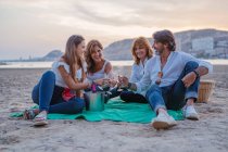 Glückliche Familie trinkt Wein beim Picknick am Strand — Stockfoto