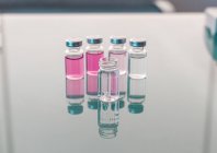Frascos para injetáveis com amostras científicas dispostos em mesa de vidro — Fotografia de Stock