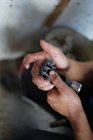 Immagine ritagliata di uomo fissaggio rasoio taglio sporco mentre si lavora in fienile in azienda — Foto stock