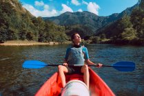 Mulher esportiva sentada com os olhos fechados em canoa vermelha e remando no declínio do rio Sella na Espanha — Fotografia de Stock