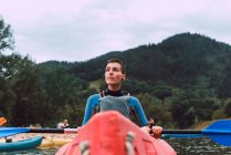Sportliche junge Frau mit kurzen Haaren sitzt im roten Kanu und paddelt auf dem Sella-Fluss in Spanien — Stockfoto