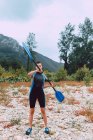 Спортивний жінка в гідрокостюм навчання з веслом, стоячи на березі річки Селла в Іспанії — стокове фото