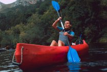 Sportive woman sitting in red canoe and paddling on Sella river decline in Spain — Stock Photo