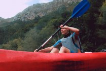 Sportive woman sitting in red canoe and paddling on Sella river decline in Spain — Stock Photo