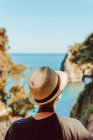 Обратный вид женщины в шляпе, стоящей у деревянных ограждений и наслаждающейся захватывающим видом на море и скалы в Ribadedeva Asturias Испании — стоковое фото