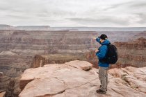 Vue arrière de l'homme avec sac à dos pointant vers la vue pittoresque du canyon aux États-Unis — Photo de stock