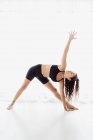 Sportive woman performing triangle yoga pose in studio — Stock Photo