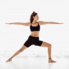 Sportive woman performing warrior yoga pose in studio — Stock Photo