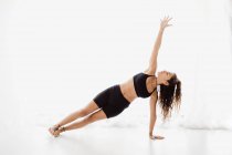 Young woman performing stretching yoga pose in studio — Stock Photo
