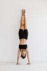 Mixed race woman performing handstand yoga pose in studio — Stock Photo