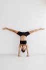 Sportive woman performing handstand yoga pose in studio — Stock Photo