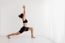 Fit femme effectuant la pose de yoga de salon élevé en studio — Photo de stock