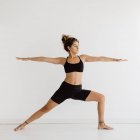 Fit woman performing warrior yoga pose in studio — Stock Photo
