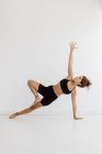 Sportliche Frau, die Side Plank Yoga vor weißem Hintergrund durchführt — Stockfoto