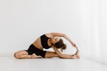 Fit mujer realizando estiramiento yoga pose sobre fondo blanco - foto de stock