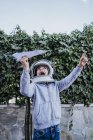 Muchacho excitado en casco astronauta jugando con avión de papel con petardo en el jardín - foto de stock