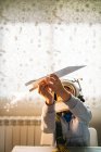 Fantasizing boy in astronaut helmet playing with paper plane at home — Stock Photo