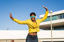 Low angle of happy African American woman jumping with hands up on street — Stock Photo