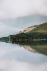 Malerische Landschaft mit Bergen und wolkenverhangenem Himmel, die sich tagsüber in ruhigem Wasser mit Segelbooten in Glencoe widerspiegelt — Stockfoto