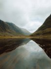 Céu nublado sobre colinas que refletem em lago com água calma no campo do Reino Unido — Fotografia de Stock