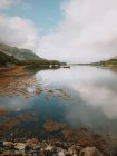 Живописный пейзаж гор и облачного неба, отраженного в спокойной воде с парусниками в Гленкоу в дневное время — стоковое фото