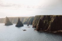 From above breathtaking landscape of cone shaped rock formations in water by coast in Duncansby Head on sunny day — Stock Photo