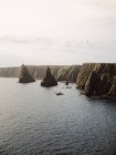 Au-dessus d'un paysage époustouflant de formations rocheuses en forme de cône dans l'eau près de la côte à Duncansby Head par temps ensoleillé — Photo de stock