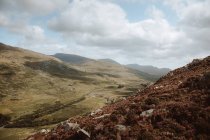 Breathtaking view of rocks and hills covered with green and brown grass and stones under overcast sky on daytime — Stock Photo