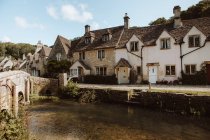 Picturesque view of medieval village Castle Combe with white and gray stone buildings by river in Dorset on sunny day — Stock Photo