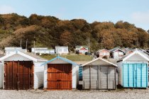 Cabanes de plage de différentes couleurs avec portes fermées par les bois sous ciel bleu le jour — Photo de stock