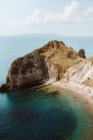 Сверху идиллический морской пейзаж с камнями под названием Дордл Дверь и люди отдыхают на берегу моря в летний день — стоковое фото