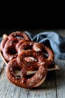 Fresh appetizing pretzels with salt arranged on scoop over old wooden surface — Stock Photo