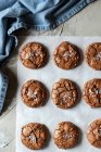 De cima composição de deliciosos biscoitos de chocolate brownie em pergaminho branco e toalha azul — Fotografia de Stock