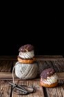 Pâtisseries maison choux avec ciseaux crème et chocolat et boule de fil disposée sur une surface en bois texture sur fond noir — Photo de stock