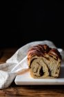 Fresh twisted bread or cinnamon babka over wooden table with striped towel on blurred background — Stock Photo