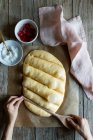 Overhead crop baker making lines with wooden spoon on dough prepared for cooking traditional pastry coca San Juan at home — Stock Photo
