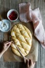 Overhead crop baker making lines with wooden spoon on dough prepared for cooking traditional pastry coca San Juan at home — Stock Photo