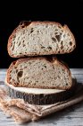 Pedaços de pão fresco saboroso caindo em guardanapo na mesa contra fundo preto — Fotografia de Stock