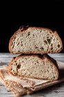 Leckeres frisches Brot fällt auf Serviette auf Tisch vor schwarzem Hintergrund — Stockfoto