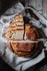 Pedaços de pão fresco saboroso caindo em guardanapo na mesa contra fundo preto — Fotografia de Stock