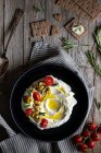 Верхняя тарелка йогурта лабне с помидорами и оливками на деревянном столе рядом с салфеткой, ложкой и хрустящими крабовыми палочками и соусом эмари — стоковое фото