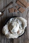 Bolachas crocantes aéreas e colher colocada perto da placa com bola de queijo labneh fresco na mesa de madeira — Fotografia de Stock