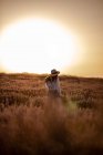 Молода жінка стоїть у квітах у великому лавандовому полі в сільській місцевості на заході сонця . — стокове фото