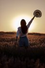 Вид ззаду на стильну молоду жінку у великому лавандовому полі в сільській місцевості на заході сонця . — стокове фото