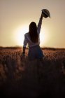 Visão traseira da elegante jovem fêmea em grande campo de lavanda no campo ao pôr do sol . — Fotografia de Stock