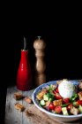 Schüssel mit leckerem Panzanella-Salat auf Tuch auf Holztisch vor schwarzem Hintergrund — Stockfoto